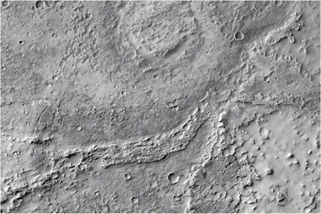 Ein mäßig erodierter, fluvialer, mäandernder Rücken mit vielen kleinen Einschlagskratern hebt sich deutlich vom umliegenden Gelände ab. Im Nordosten tritt er aus einem kleinen Tal hervor, wird nach Westen hin deutlicher und verschwindet schließlich. Die ausgeprägte Krümmung des Rückens spricht für eine ehemalige Flussschleife (Mäander). Nördlich davon befindet sich eine runde, flache Struktur – vermutlich ein Einschlagskrater, der einst mit Wasser oder Sediment gefüllt war.Copyright/Quelle: CTX image: MurrayLab_V01_E020_N-20_Mosaic. Credit: NASA/JPL/MSSS/The Murray Lab